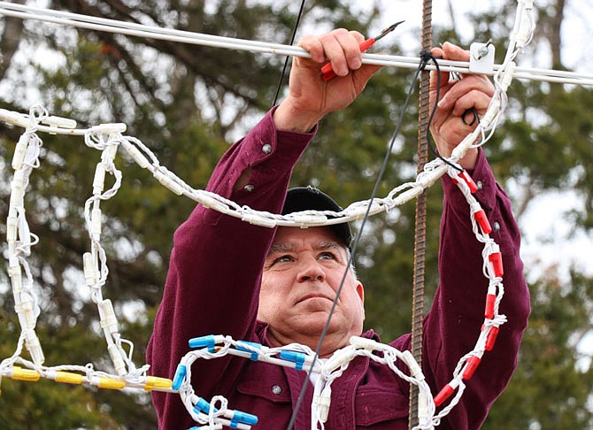 Jeff Buker on Thursday cuts a piece of string from a light decoration, which was a part of the Binder Park Festival of Lights display. Buker, along with three other volunteers, began breaking down the light display Wednesday and will continue their work throughout the weekend.