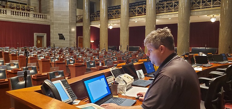 Chris Ortmeyer sits behind the rostrum on the Missouri House floor configuring lawmakers' voting system for the 2020 session.