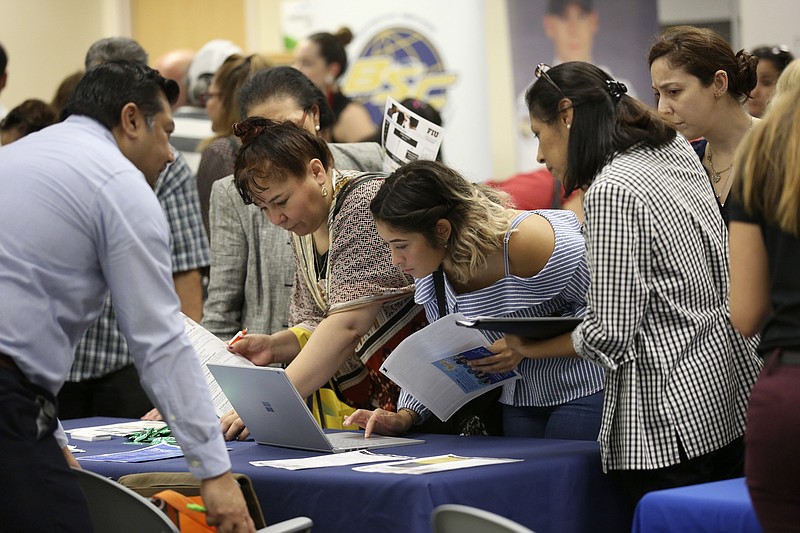 FILE - In this Sept. 18, 2019, file photo job applicants looks at jobs available at Florida International University during a job fair in Miami. On Wednesday, Jan. 8, 2020, payroll processor ADP reports on how many jobs its survey estimates U.S. companies added in December. (AP Photo/Lynne Sladky, File)