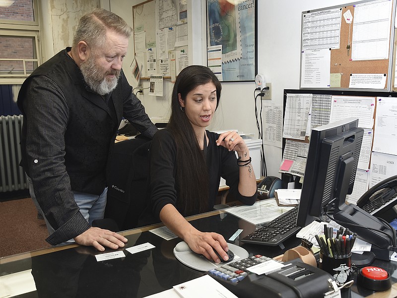 Vincent Owens offers assistance to his replacement, Sonya Schroeder, who will now serve as supervisor of customer services at the High Street Post Office. Owens recently retired after 35 years of service to the agency but was at the facility Friday for a brief retirement ceremony.