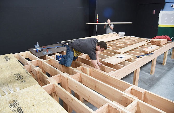 Mike Gorman, in the background, carries in lumber as Taylor Hume secures the underneath of the stage. Both volunteered earlier in the week to help Capital City Productions try to meet the deadline for their first play in the new location on Wicker Lane.