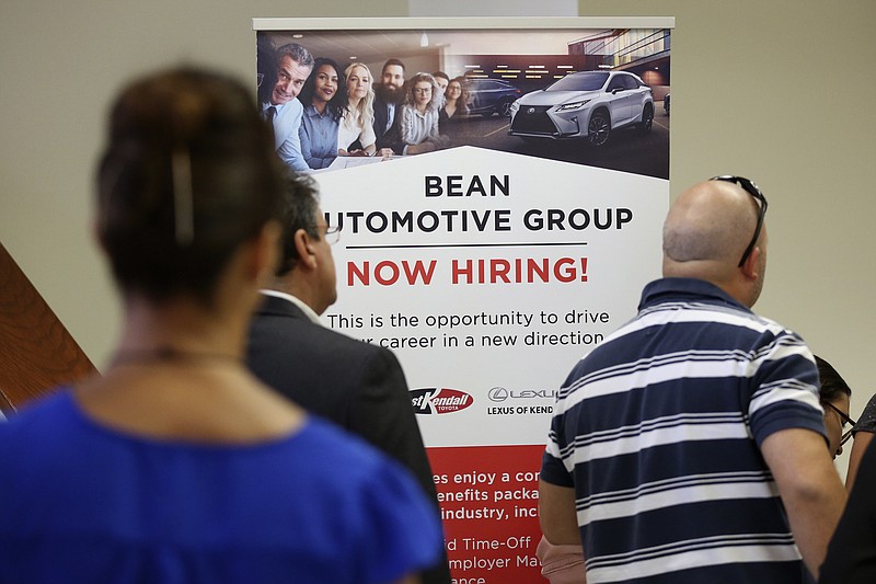 FILE - In this Sept. 18, 2019, file photo people stand in line to inquire about jobs available at the Bean Automotive Group during a job fair in Miami. On Friday, Jan. 10, 2020, the U.S. government issues the December jobs report. (AP Photo/Lynne Sladky, File)