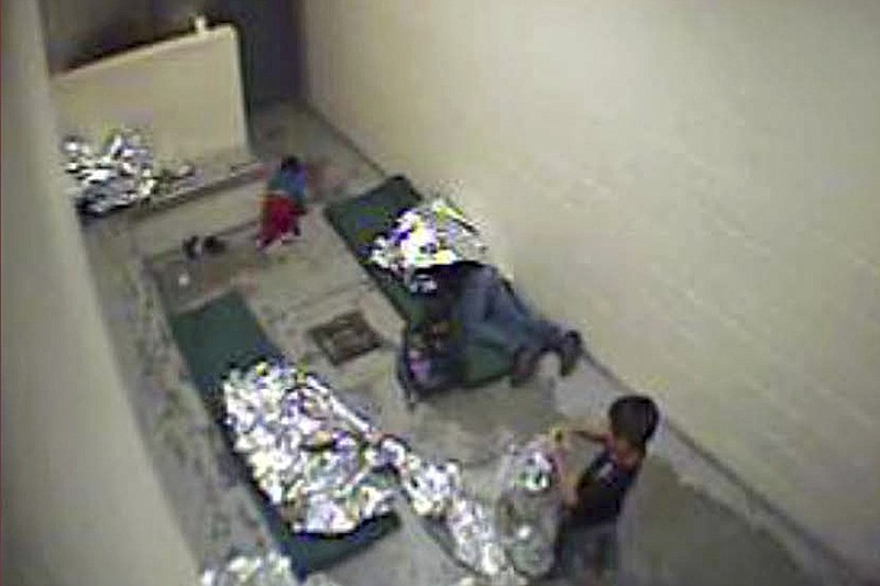 FILE - This Sept. 2015, file image made from U.S. Border Patrol surveillance video shows a child crawling on the concrete floor near the bathroom area of a holding cell, and a woman and children wrapped in Mylar sheets at a U.S. Customs and Border Protection station in Douglas, Ariz. A years-old lawsuit challenging detention conditions in several of the Border Patrol’s Arizona stations will go to trial Monday, Jan. 13, 2020, as the agency as a whole has come under fire following several migrant deaths. The lawsuit was first filed in June 2015 and applies to eight Border Patrol facilities in Arizona where attorneys say migrants are held in unsafe and inhumane conditions. (U.S. Border Patrol via AP, File)