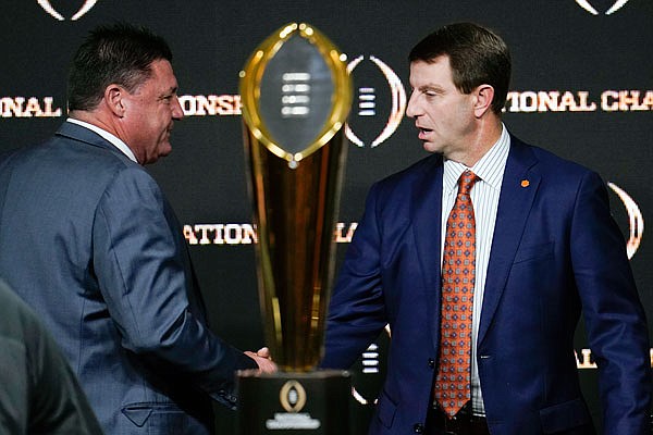 LSU head coach Ed Orgeron (left) and Clemson head coach Dabo Swinney shake hands near the trophy after a news conference Sunday for tonight's College Football Playoff national championship game in New Orleans.