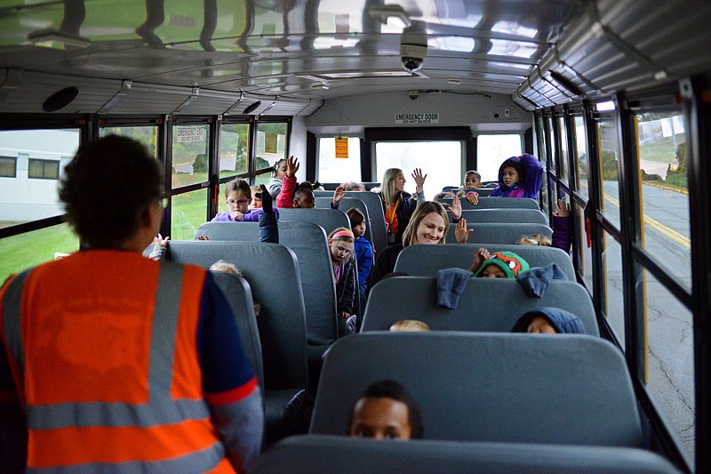 In this Oct. 30, 2019, photo, students raise their hands to answer safety questions from location safety manager Patty Rodwhick, left, during a First Student Safety Dog Bus Tour at Moreau Heights Elementary School in Jefferson City.