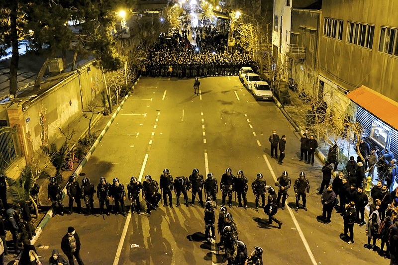 In this photograph taken Saturday, Jan. 11, 2020, Iranian police officers take position while protesters gather in front of Amir Kabir University in Tehran, Iran, to remember victims of a Ukrainian airplane shot down by an Iranian missile. Online videos purported to show Monday, Jan. 13, 2020, that Iranian security forces fired both live ammunition and tear gas to disperse demonstrators protesting against the Islamic Republic's initial denial that it shot down a Ukrainian jetliner. (AP Photo)