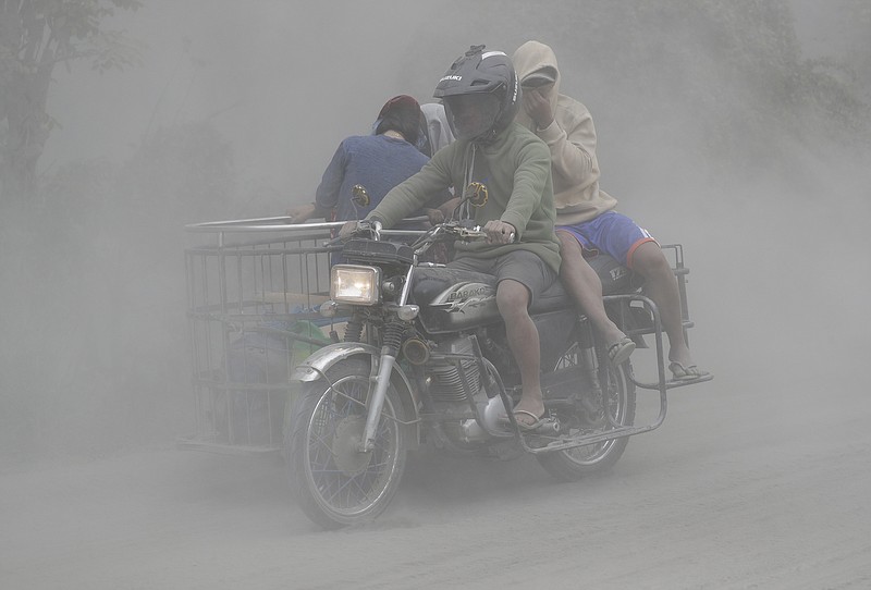 A family rides their motorcycle through clouds of ash as they evacuate to safer grounds as Taal volcano in Tagaytay, Cavite province, southern Philippines on Monday, Jan. 13, 2020. Red-hot lava is gushing from the volcano after a sudden eruption of ash and steam that forced residents to flee and shut down Manila’s airport, offices and schools. (AP Photo/Aaron Favila)