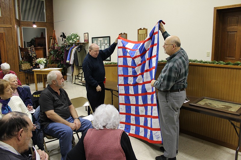 <p>Democrat photo/Austin Hornbostel</p><p>Paul, left, and David Jungmeyer show the crowd a quilt signed by every United States governor from 1995-1996, including Missouri Gov. Mel Carnahan, during the Moniteau County Historical Society’s annual show & tell presentation. The quilt has been donated to the Historical Society for display.</p>