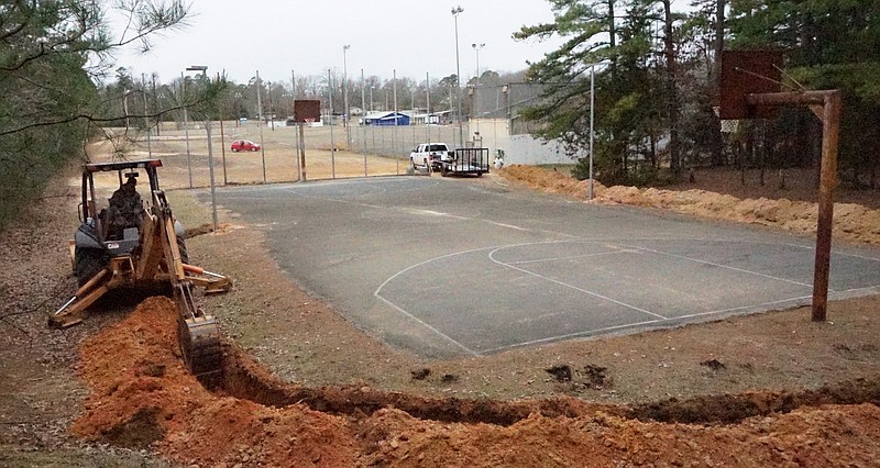 The trench work for lights at the Crow-Heath basketball court in Linden is being done by Billy Hankins. The digging is for the installation of the electrical lines placed underground around the court's edge. The poles for the lighting fixtures can be seen in the mid-point of the court.
