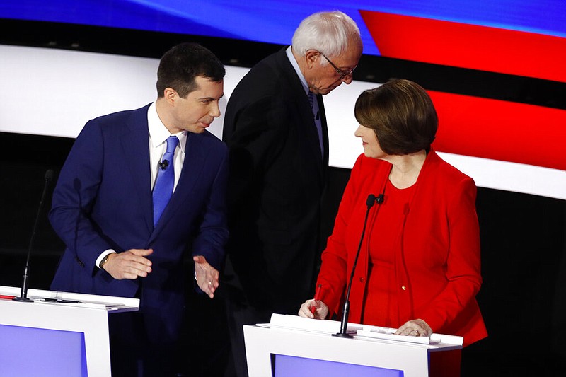 Democratic presidential candidates former South Bend Mayor Pete Buttigieg, left, and Sen. Amy Klobuchar, D-Minn., talk while Sen. Bernie Sanders, I-Vt., heads off stage at a break Tuesday, Jan. 14, 2020, during a Democratic presidential primary debate hosted by CNN and the Des Moines Register in Des Moines, Iowa. (AP Photo/Patrick Semansky)