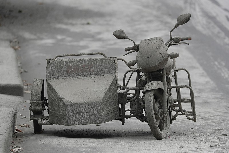 A motorcycle that is covered in volcanic ash is left by it’s owner at a deserted village near Taal volcano in Talisay, Batangas province, southern Philippines on Friday Jan. 17, 2020. Taal volcano remains life-threatening despite weaker emissions and fewer tremors, an official said Friday and advised thousands of displaced villagers not to return to the danger zone. (AP Photo/Aaron Favila)