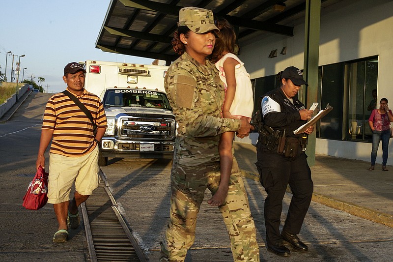 Jose Gonzalez, left, follows his 5-year-old daughter, carried by a police officer, as they leave a hospital in Santiago, Panama, Thursday, Jan. 16, 2020. Gonzalez's wife and five of their children are among seven people killed in a religious ritual in the Ngabe Bugle indigenous community. According to local prosecutor Rafael Baloyes indigenous residents were rounded up by lay preachers and tortured, beaten, burned and hacked with machetes to make them "repent their sins." (AP Photo/Arnulfo Franco)