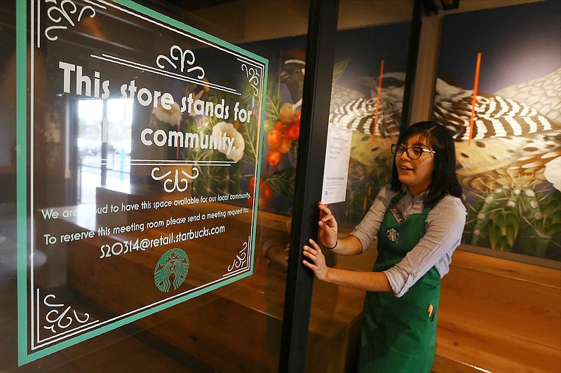 In this Wednesday, Jan. 15, 2020, photo, Belith Ariza, a barista trainer at Starbucks, opens the doors to the community meeting space at a local Starbucks Community Store, in Phoenix. The Seattle-based company plans to open or remodel 85 stores by 2025 in rural and urban communities across the U.S. That will bring to 100 the total number of community stores Starbucks has opened since it announced the program in 2015. (AP Photo/Ross D. Franklin)