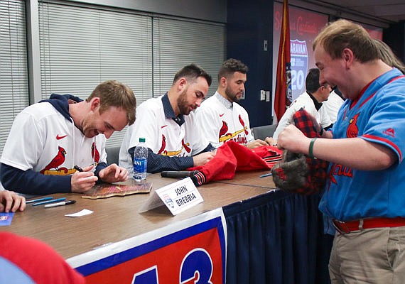 Dakota Wilmes (right) jumps up and down as John Brebbia signs a Cardinals plaque in the shape of Missouri for him at the Cardinals Caravan event Friday at the Missouri Farm Bureau. Wilmes was accompanied by his mother, Michelle, and his younger sister, Marya. Michelle Wilmes later won eight Cardinals game tickets during the raffle portion of the Caravan.