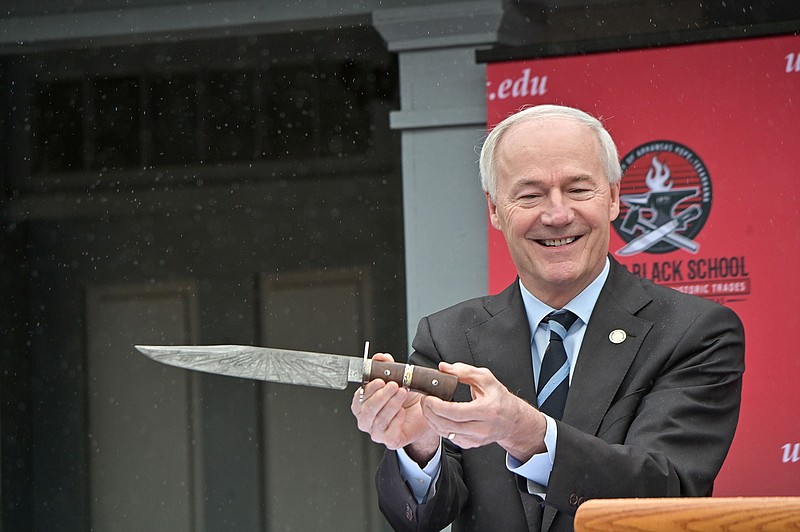 Arkansas Gov. Asa Hutchinson holds a commemorative Bowie knife dubbed Arkansas No. 1 on Friday during the dedication of the James Black School of Bladesmithing and Historic Trades at Historic Washington State Park. Arkansas No. 1 was made with 1,836 layers of steel to commemorate 1836, the year Arkansas became a state. Its blade contains steel from a handrail at the Statue of Liberty, and its handle is made from a tree at James Black's gravesite. 