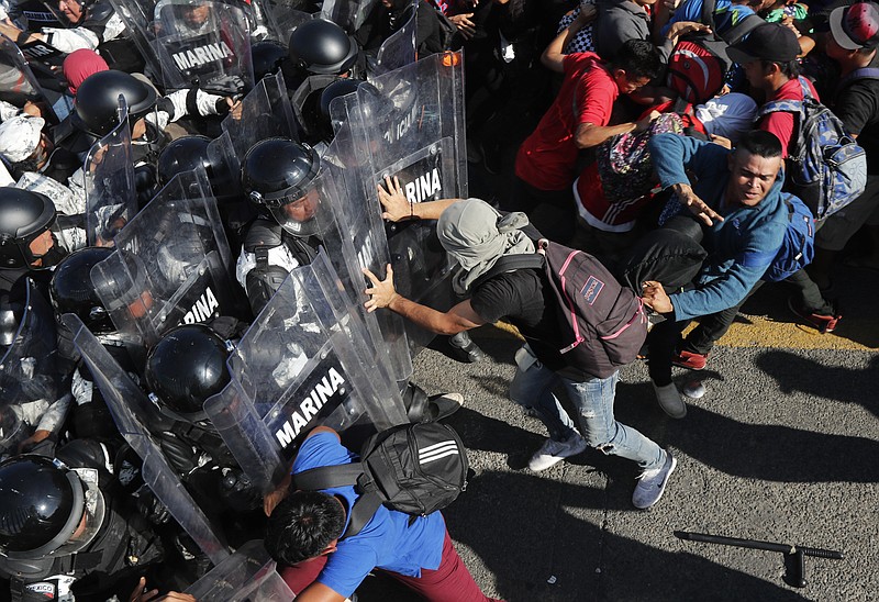 Migrants charge on Mexican National Guardsmen at the border crossing between Guatemala and Mexico in Tecun Uman, Guatemala, Saturday, Jan. 18, 2020. More than a thousand Central American migrants surged onto a bridge spanning the Suchiate River that marks the border between both countries as Mexican security forces attempted to impede their journey north. (AP Photo/Marco Ugarte)