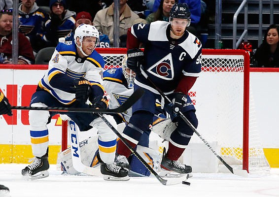 Blues defenseman Carl Gunnarsson clears the puck from in front of the net as Gabriel Landeskog of the Avalanche looks on in the second period of Saturday afternoon's game in Denver.