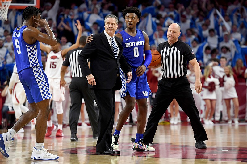 Kentucky players Ashton Hagans (0) and Immanuel Quickley (5) walk with head coach John Calipari, center, as he heads to the locker room after being ejected during the second half of an NCAA college basketball game against Arkansas, Saturday, Jan. 18, 2020, in Fayetteville, Ark. (AP Photo/Michael Woods)