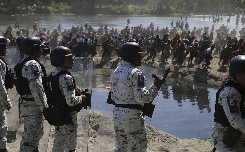 Mexican National Guards stand on the bank of the Suchiate River where Central American migrants are crossing from Guatemala, near Ciudad Hidalgo, Mexico, Monday, Jan. 20, 2020. More than a thousand Central American migrants hoping to reach United States marooned in Guatemala are walking en masse across a river leading to Mexico in an attempt to convince authorities there to allow them passage through the country. (AP Photo/Marco Ugarte)