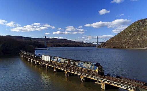 FILE - In this April 26, 2018, file photo a CSX Transportation locomotive pulls a train of tank cars across a bridge on the Hudson River along the edge of Bear Mountain State Park near Fort Montgomery, N.Y. This year’s scheduled completion of a $15 billion automatic railroad braking system will bolster the industry’s argument for eliminating one of the two crew members in most locomotives. But labor groups argue that single-person crews would make trains more accident prone. (AP Photo/Julie Jacobson, File)