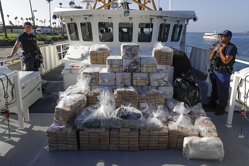 In this Aug. 29, 2019, file photo, members of the Coast Guard stand near seized cocaine in Los Angeles. The nation's drug addiction crisis has been morphing in a deadly new direction: more Americans struggling with meth and cocaine. Now the government will allow states to use federal money earmarked of the opioid crisis to help people addicted to those drugs as well. The change to a $1.5 billion opioid grants program was buried in a massive spending bill that Congress passed late in 2019.