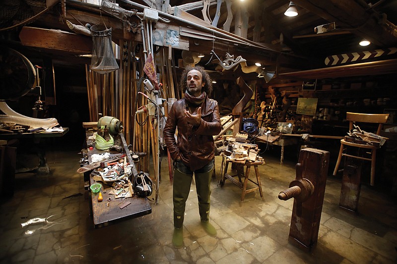 In this photo taken on Sunday, Nov. 17, 2019, Paolo Brandolisio stands in his oars flooded laboratory, in Venice, Italy. Venetians are fed up with what they see as an inadequate to the city's mounting problems: record-breaking flooding, damaging cruise ship traffic and over-tourism. They feel largely left to their own devices, and with ever fewer Venetians living in the historic part of the city to defend its interests and keep it from becoming a theme park or museum.(AP Photo/Luca Bruno)