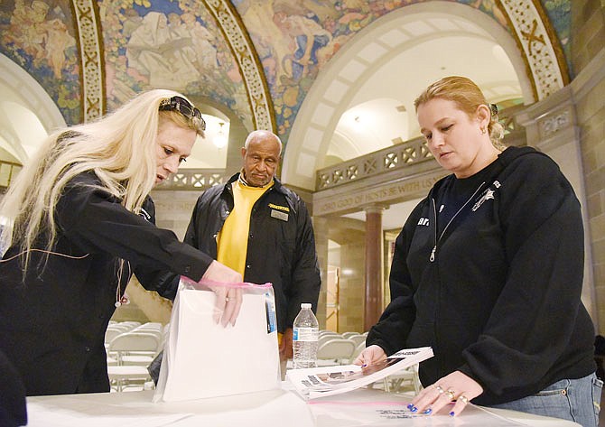 Todar Wazir, background middle, looks on and offers assistance to Victoria Ferguson, left, and Carrie Ballard as they place information in packets to be delivered to legislators. Ferguson is the founder of Justice 4 Inmates, an advocacy group for families of inmates with medical or treatment issues. She was to speak at a rally scheduled Thursday in the Capitol Rotunda, but due to weather conditions throughout the state, most were unable to make it to the event. Ballard and others who did attend the gathering were passionate about the cause and addressed reporters' questions about the group's cause and what they hoped to achieve.