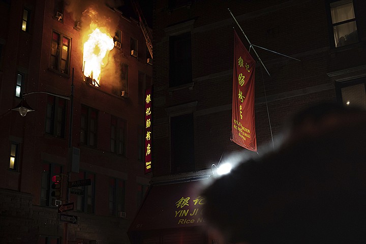 Fire blows out of a window in the Chinatown section of New York, Thursday, Jan. 23, 2020. New York City firefighters battled a raging blaze at a building in the city's Chinatown area Thursday night, Firefighters said they were called about 8:45 p.m. to 70 Mulberry Street for a fire on the fourth and fifth floors of the building, NYFD officials said. (AP Photo/Robert Bumsted)