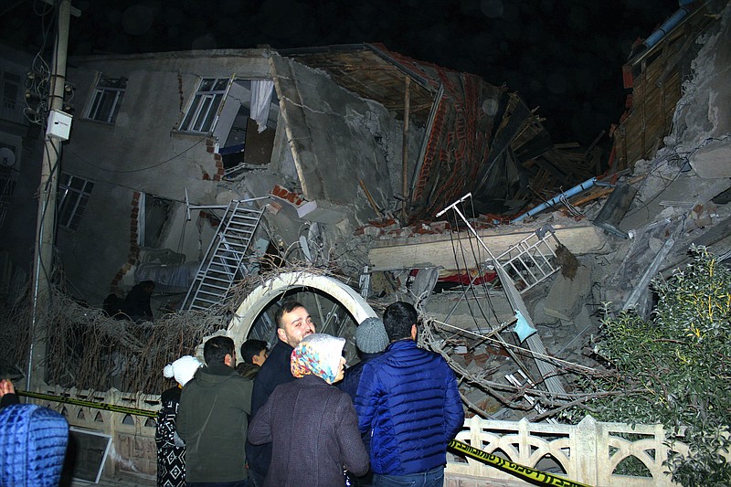 People look at a collapsed building after a 6.8 earthquake struck Elazig city centre in the eastern Turkey, Friday, Jan. 24, 2020. An earthquake with a preliminary magnitude of 6.8 rocked eastern Turkey on Friday, causing some buildings to collapse and killing at least four people, Turkish officials said. (IHA via AP)