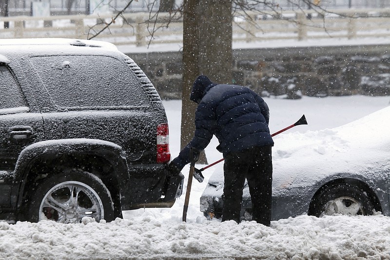 Man cleans car with brush during snow storm in New York. (Dreamstime/TNS)