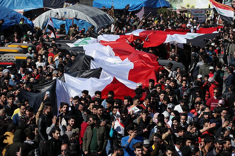 Anti-government protesters hold a huge Iraqi flag as they gather during a protest in Tahrir Square in Baghdad, Iraq, Sunday, Jan. 26, 2020. (AP Photo/Hadi Mizban)
