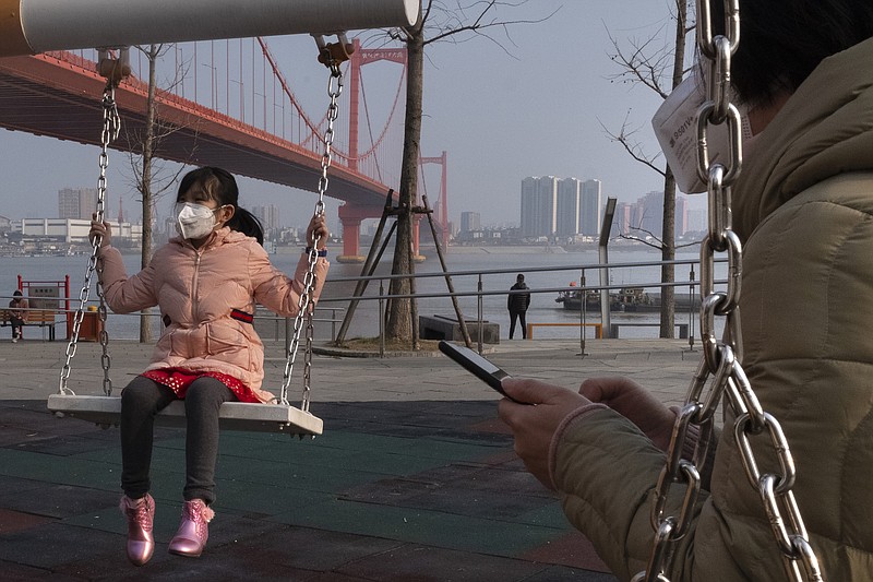 A girl wears a face mask as she play on a swing near the Yingwuzhou Yangtze River Bridge in Wuhan in central China's Hubei Province, Wednesday, Jan. 29, 2020. Countries began evacuating their citizens Wednesday from the Chinese city hardest-hit by a new virus that has now infected more people in China than were sickened in the country by SARS. (AP Photo/Arek Rataj)