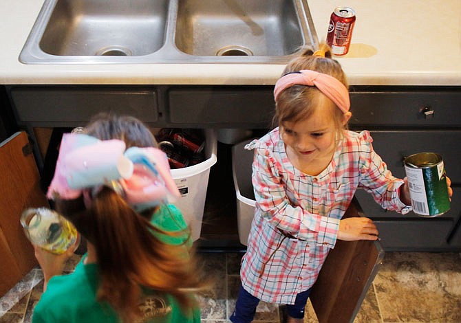 Josie Roush, 7, left, and Millie Roush, 5, demonstrate Friday how they sort the recyclables into different bins at their home in St. Martins. The girls get to keep the change they make from turning recyclables into the recycling center and are allowed to spend it on whatever they'd like at the convenience store. 