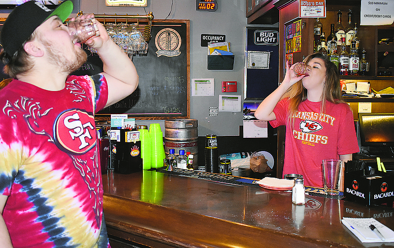 At left, Skylar Smock, J. Pfenny's kitchen manager, and manager Nikki Langwith do a shot before the expected Super Bowl party rush Sunday. Some fans had their seats at the sports pub more than an hour before the game started.