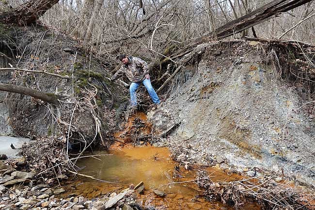 Mike Mueller, unit chief with the Missouri Department of Natural Resources' Land Reclamation division, investigates the source of a bright-red substance leaching into Stinson Creek. He suspects the source is an abandoned mine.