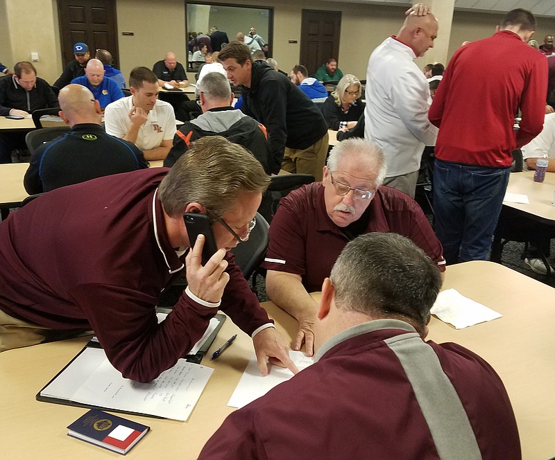 Atlanta head coach and athletic director Matt McClure talks on the phone to schedule an opponent for the upcoming season with the help of Atlanta ISD Superintendent Sidney Harrist, right, and a Rabbit assistant coach after the 2020-22 UIL District Assignment and Reclassification packet were released Monday morning at the Region 8 Education Service Center in Pittsburg, Texas.