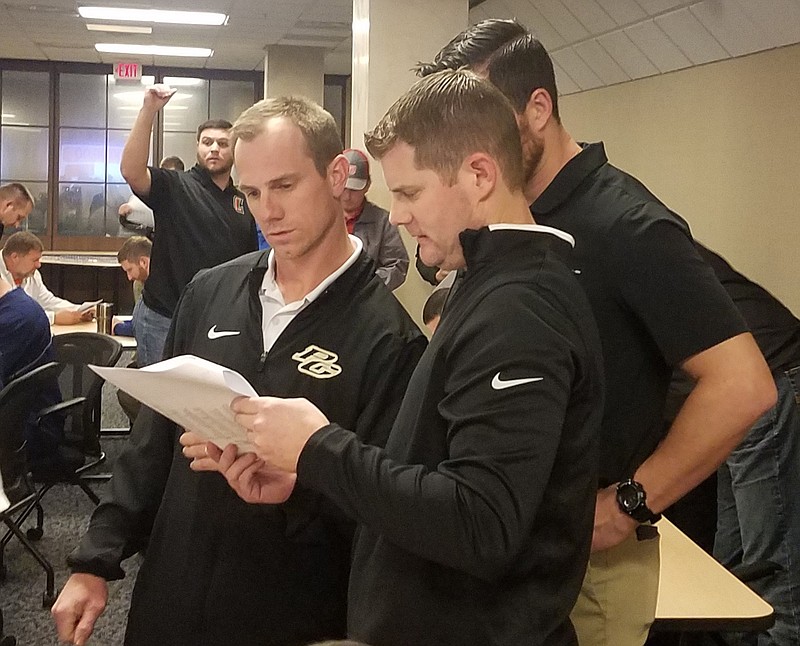 Pleasant Grove defensive coordinator Clint Fuller, left, and assistant head coach/offensive coordinator Justin Gibson look through the 2020-22 UIL District Assignment and Reclassification packet, which was released Monday morning at the Region 8 Education Service Center in Pittsburg, Texas.