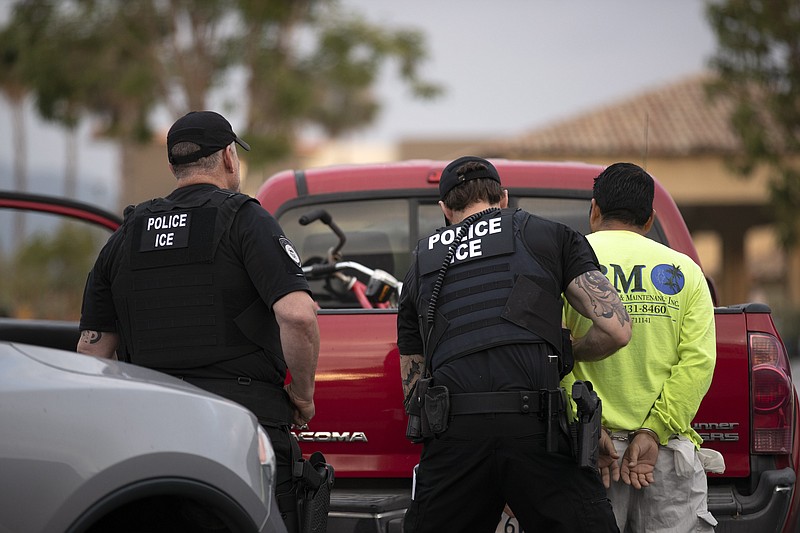 In this July 8, 2019, photo, a U.S. Immigration and Customs Enforcement (ICE) officers detain a man during an operation in Escondido, Calif. A federal judge has prohibited U.S. immigration authorities from relying on databases deemed faulty to ask law enforcement agencies to hold people in custody, a setback for the Trump administration that threatens to hamper how it carries out arrests. (AP Photo/Gregory Bull)