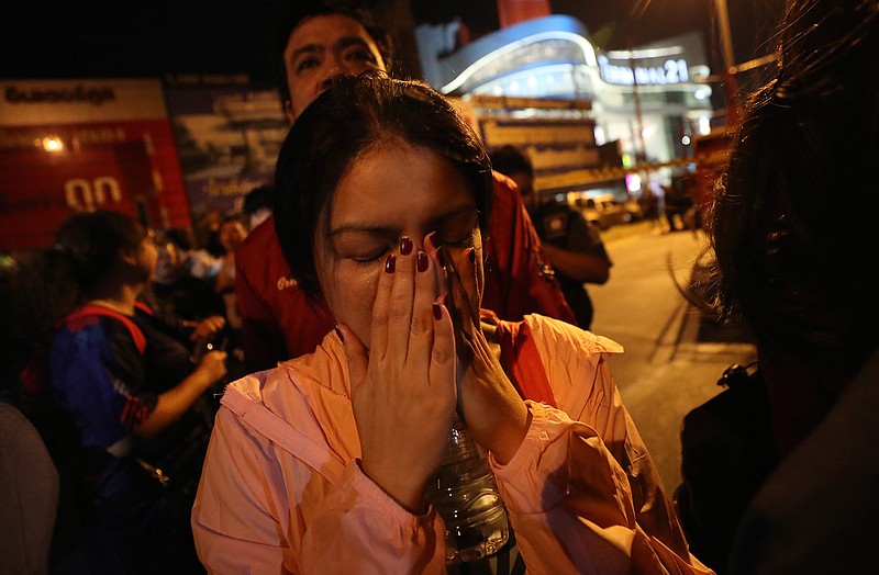 A woman who was able to get out of the Terminal 21 Korat mall gestures with her hands on her face Sunday, Feb. 9, 2020, in Nakhon Ratchasima, Thailand. A soldier who holed up in the popular shopping mall in northeastern Thailand shot multiple people on Saturday, killing at least 29 and injuring 58 others before he was shot dead, officials said.