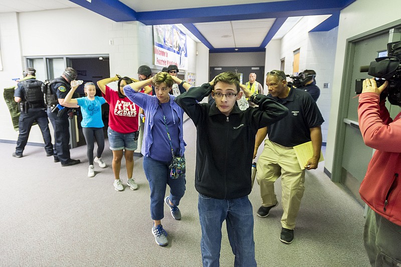 FILE - In this Friday June 9, 2017 file photo, students are led out of school as members of the Fountain Police Department take part in an Active Shooter Response Training exercise at Fountain Middle School in Fountain, Colo. The nation's two largest teachers unions want schools to revise or eliminate active shooter drills, asserting Tuesday, Feb. 11, 2020 that they can harm students' mental health and that there are better ways to prepare for the possibility of a school shooting. (Dougal Brownlie/The Gazette via AP, File)