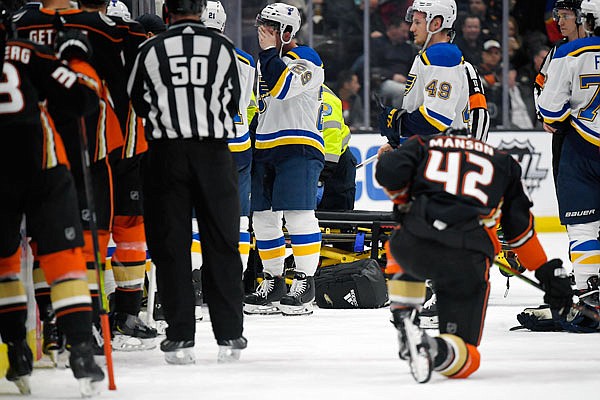 Blues defenseman Vince Dunn wipes his faces as Ducks defenseman Josh Manson kneels on the ice as Blues defenseman Jay Bouwmeester, who suffered a medical emergency, is worked on by medical personnel during the first period of Tuesday night's game in Anaheim, Calif.