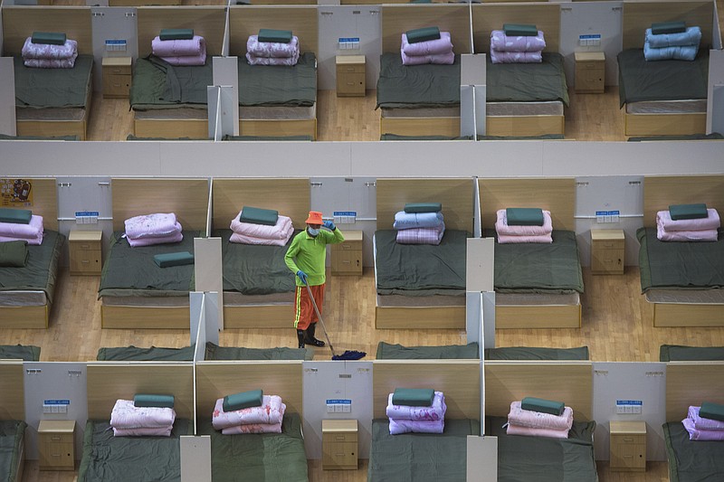 In this photo released by Xinhua News Agency, a worker cleans the floor of a temporary hospital with 1,100 beds converted from the Wuhan Sports Center in Wuhan in central China's Hubei Province, Wednesday, Feb. 12, 2020. Without enough facilities to handle the number of cases of viral infection, Wuhan has been building prefabricated hospitals and converting a gym and other large spaces to house patients and try to isolate them from others. (Xiao Yijiu/Xinhua via AP)