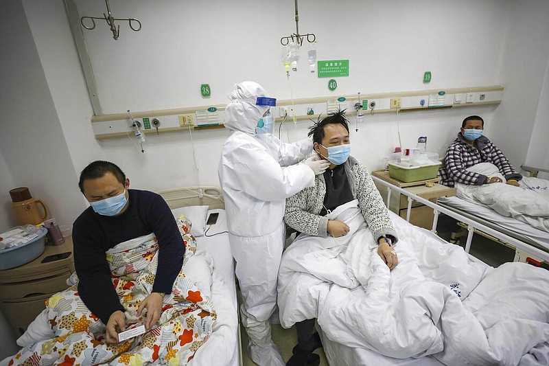 A doctor checks the conditions of a patient in Jinyintan Hospital, designated for critical COVID-19 patients, in Wuhan in central China's Hubei province Thursday, Feb. 13, 2020. China on Thursday reported 254 new deaths and a spike in virus cases of 15,152, after the hardest-hit province of Hubei applied a new classification system that broadens the scope of diagnoses for the outbreak, which has spread to more than 20 countries. (Chinatopix Via AP)
