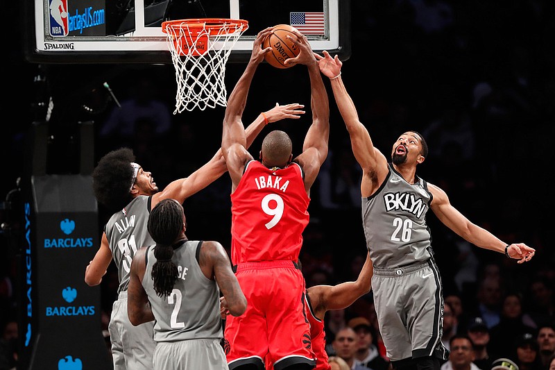 Brooklyn Nets center Jarrett Allen (31) and Nets guard Spencer Dinwiddie (26) defend Toronto Raptors center Serge Ibaka (9) as Nets forward Taurean Prince (2) watches from the floor during the second half of an NBA basketball game, Wednesday, Feb. 12, 2020, in New York. The Nets defeated the Raptors 101-91, ending Toronto's 15-game winning streak. (AP Photo/Kathy Willens)