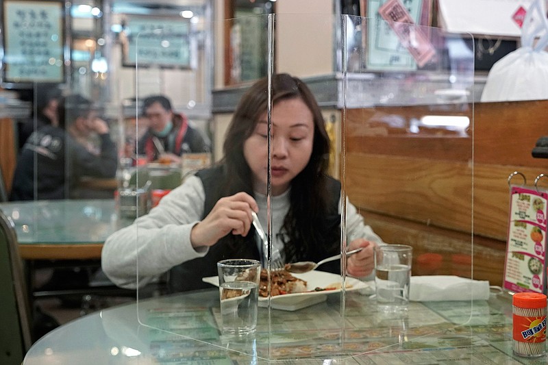 Customer has lunch with a transparent plastic panel setup on the table to isolate her from others in hopes of stopping the spread of the coronavirus in a Hong Kong, Wednesday, Feb. 12, 2020. China's ruling Communist Party needs to make a politically fraught decision: Admit a viral outbreak isn't under control and cancel this year's highest-profile official event. Or bring 3,000 legislators to Beijing next month and risk fueling public anger at the government's handling of the disease. (AP Photo/Kin Cheung)