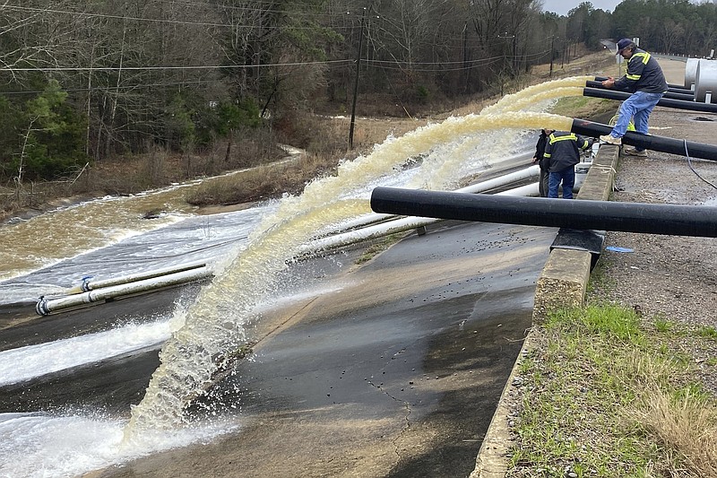 Crews work to replace drainage pipes at the Oktibbeha County Lake dam in Starkville, Miss., as heavy rains cause water levels to rise, Tuesday, Feb. 11, 2020. In eastern Mississippi, officials in Starkville said the water at Oktibbeha County Lake had once again reached a critical level just weeks after heavy rains caused a mudslide that put the earthen dam in danger of failing. (Ryan Phillips/The Starkville Daily News via AP)