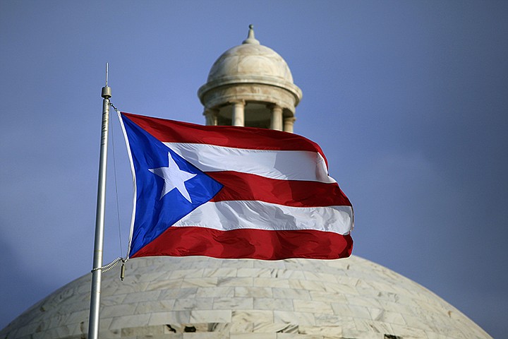 In this July 29, 2015 file photo, the Puerto Rican flag flies in front of Puerto Rico's Capitol as in San Juan, Puerto Rico. A senior Puerto Ricon official said Tuesday, Feb. 11, 2020, that the island's government has lost more than $2.6 million after falling for an email phishing scam. (AP Photo/Ricardo Arduengo, File)