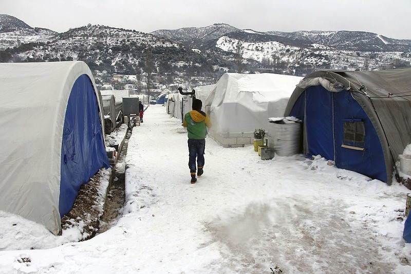 This Thursday, Feb. 13, 2020 photo released by the opposition Syrian Civil Defense rescue group, also known as White Helmets, which has been authenticated based on its contents and other AP reporting, shows Syrian walking outside their tents at a displaced people camp near Turkish border, in Idlib province, Syria. A military offensive on an opposition-controlled region of northwestern Syria has created one of the worst catastrophes for civilians in the country's long-running war, sending hundreds of thousands of people fleeing, many of them sleeping in open fields and under trees in freezing temperatures. (Syrian Civil Defense White Helmets via AP)