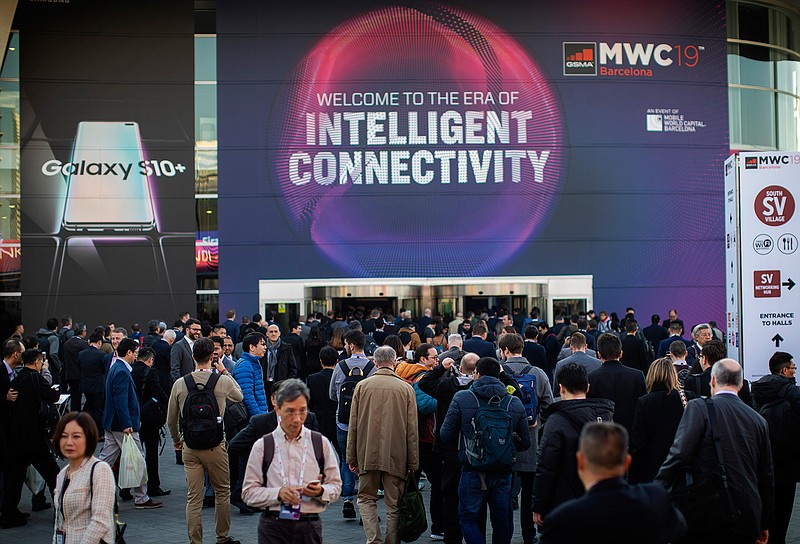 In this Feb. 25, 2019 photo, attendees walk to enter at the Mobile World Congress wireless show, in Barcelona, Spain. Organizers of the world's biggest mobile technology fair are pulling the plug over worries about the viral outbreak from China. The annual Mobile World Congress show will no longer be held as planned in Barcelona, Spain, on Feb. 24-27, 2020. (AP Photo/Emilio Morenatti)