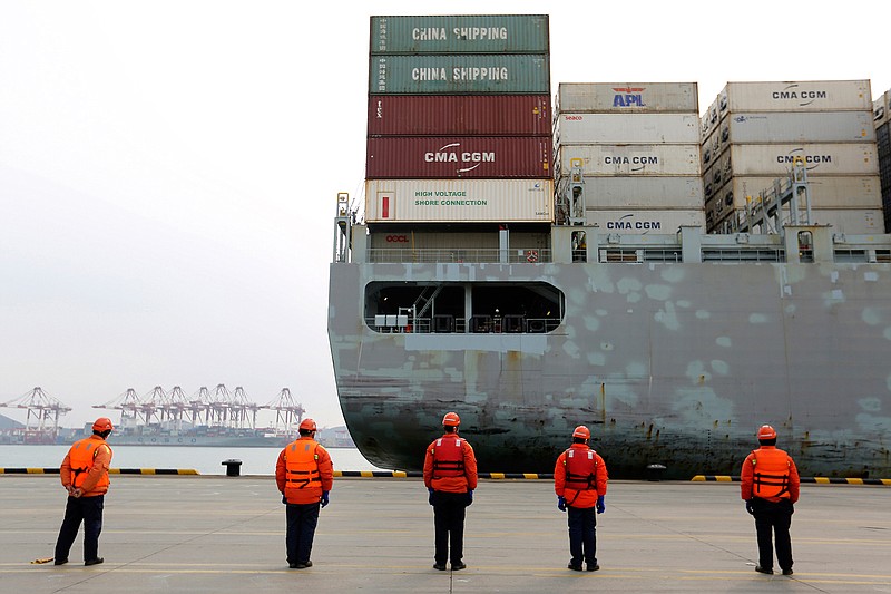 In this Feb. 4, 2020, file photo, workers watch a container ship arrive at a port in Qingdao in east China's Shandong province. Factories across China are still closed to try to limit spread of the coronavirus, leaving business owners in limbo. (Chinatopix via AP, File)